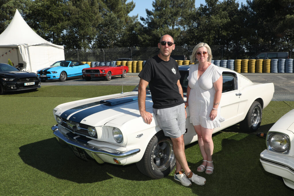 Isabelle Avoie, déléguée régionale du Club Mustang pour les Pays de Loire et son mari, également membre du club, posent devant leur exemplaire au Mans Classic 2026.